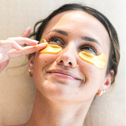 Woman applying Vegan Gold eye masks  to her eyes.
